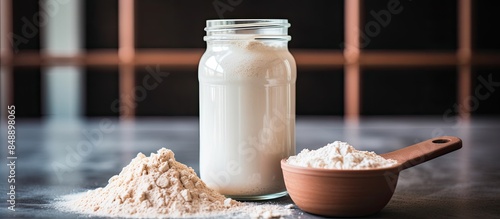 Close up of whey isolate protein scoop beside a clear shaker bottle highlighting the protein content within the scoop in a copy space image photo