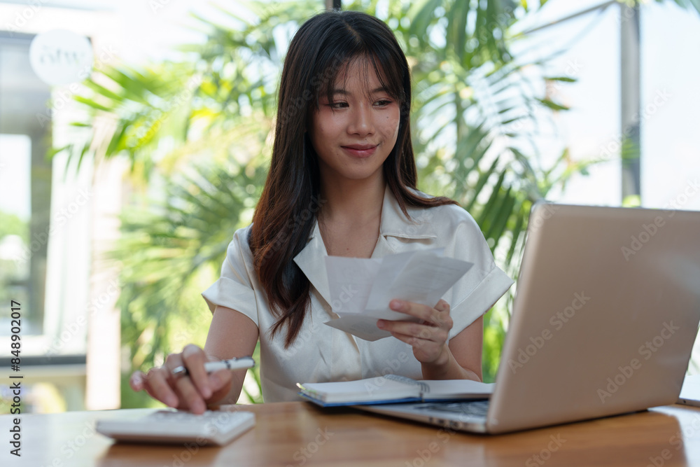 Woman working outside using calculator and laptop Attentive Asian woman checks taxes, rent, financial expenses to pay bills Control your finances online Accounting work concept. Woman working outside using calculator and laptop Attentive Asian woman checks taxes, rent, financial expenses to pay bills Control your finances online Accounting work concept.