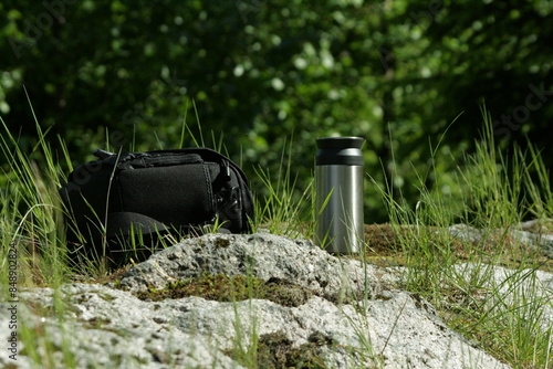 The photo shows the style of travel, a thermo cup and a camera. photo