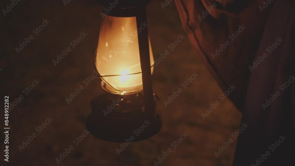 A man in a cape carries a kerosene lamp that burns in the dark and sways A man in a cape carries a kerosene lamp that burns in the dark and sways