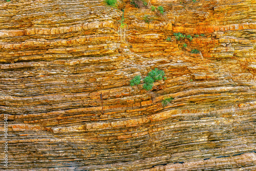 yellow orange rock stone wall close up with layers of rock formation. nature background for wallpaper and design photo