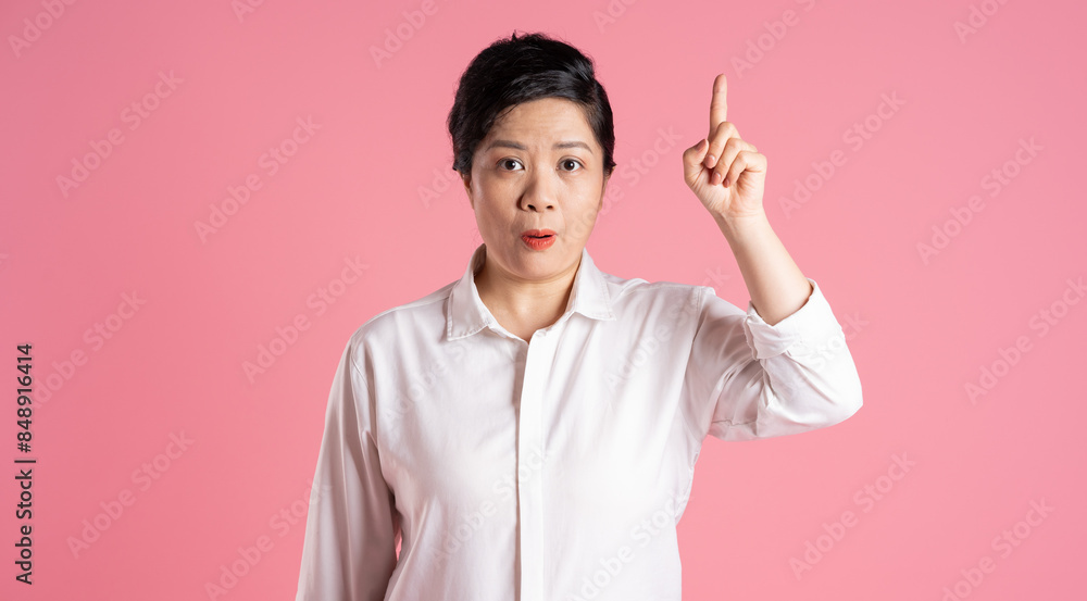 Image of older Asian businesswoman posing on pink background Image of older Asian businesswoman posing on pink background