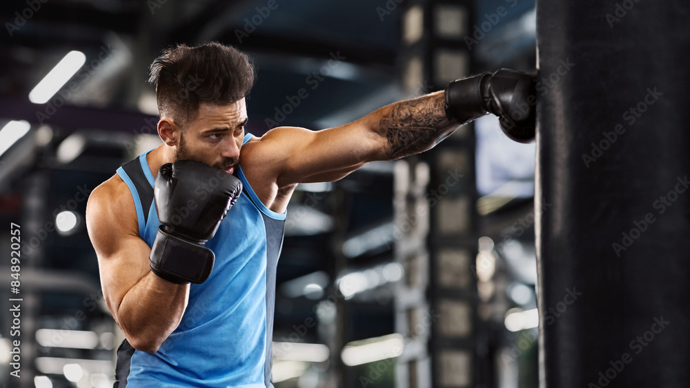 Young sportsman boxing workout at gym, guy punching boxing bag, free space Young sportsman boxing workout at gym, guy punching boxing bag, free space