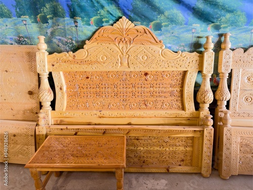 Handcrafted Wooden Bed Frame and Matching Table. Elegant Wooden Bed Frame with Carved Detailing in a furniture workshop.