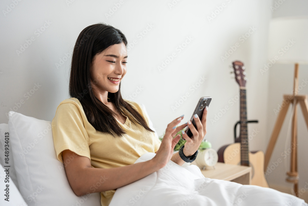 Asian attractive woman using mobile phone on bed at home in morning. Asian attractive woman using mobile phone on bed at home in morning.