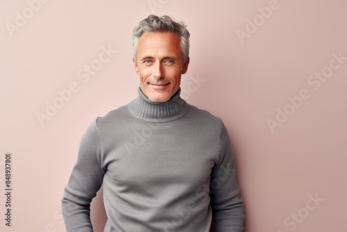 Portrait of a satisfied man in his 50s wearing a classic turtleneck sweater in front of minimalist or empty room background