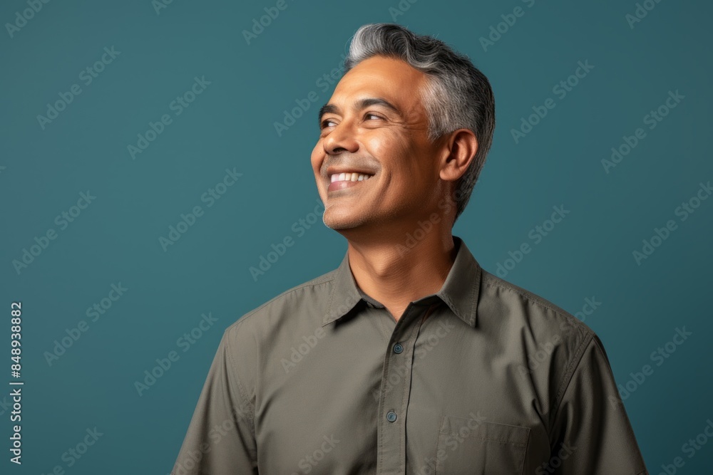 Portrait of a satisfied indian man in his 50s sporting a breathable hiking shirt in minimalist or empty room background Portrait of a satisfied indian man in his 50s sporting a breathable hiking shirt in minimalist or empty room background