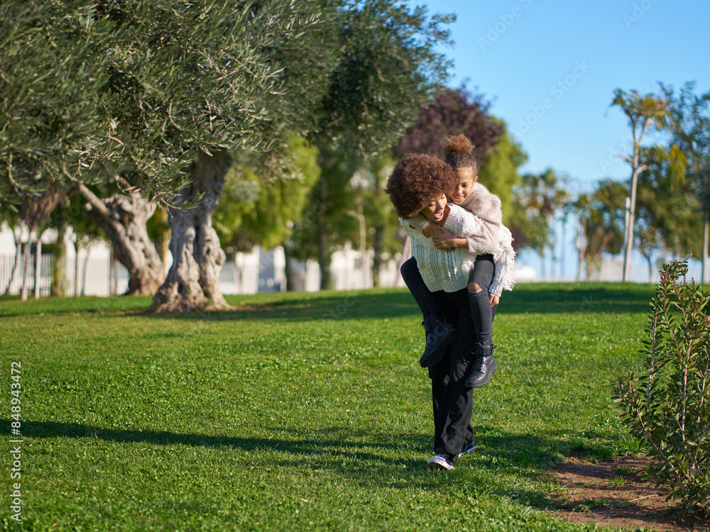 A little girl is being carried by her sister in a park A little girl is being carried by her sister in a park