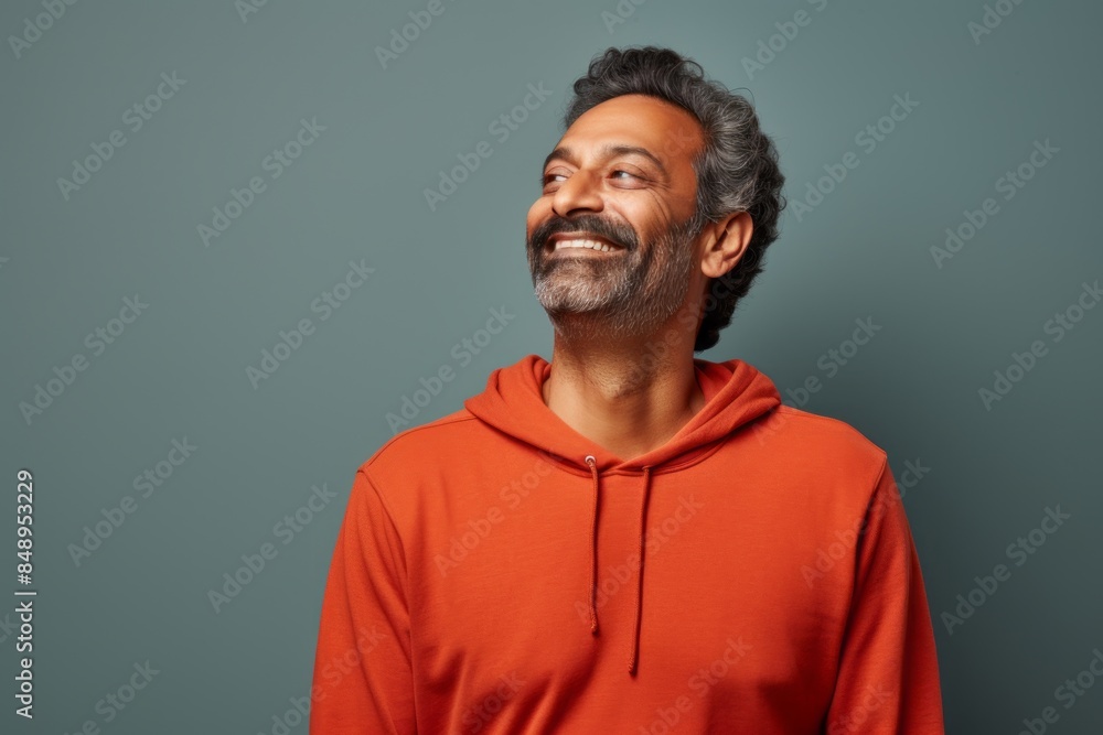 Obraz premium Portrait of a blissful indian man in his 40s dressed in a comfy fleece pullover in solid color backdrop