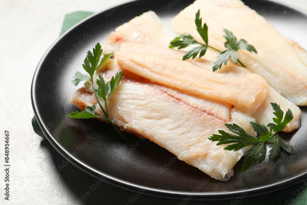 Plate with raw cod fish and parsley on light table, closeup Plate with raw cod fish and parsley on light table, closeup