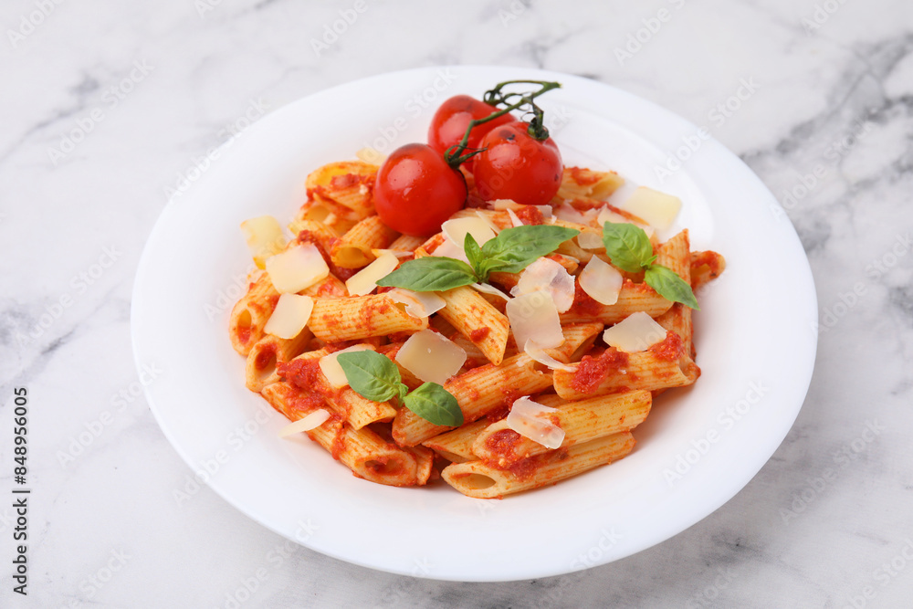 Tasty pasta with tomato sauce, cheese and basil on white marble table Tasty pasta with tomato sauce, cheese and basil on white marble table