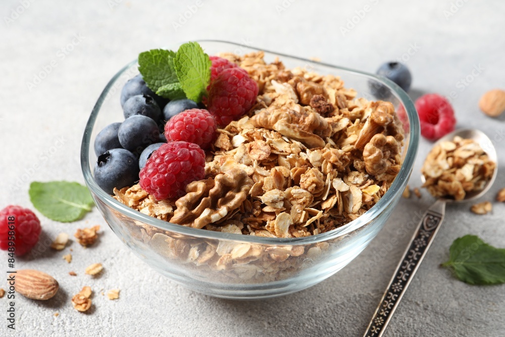 Tasty granola with berries, nuts and mint on grey table Tasty granola with berries, nuts and mint on grey table