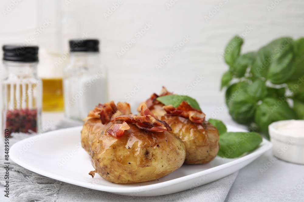 Delicious baked potatoes with bacon and basil on grey table, closeup Delicious baked potatoes with bacon and basil on grey table, closeup