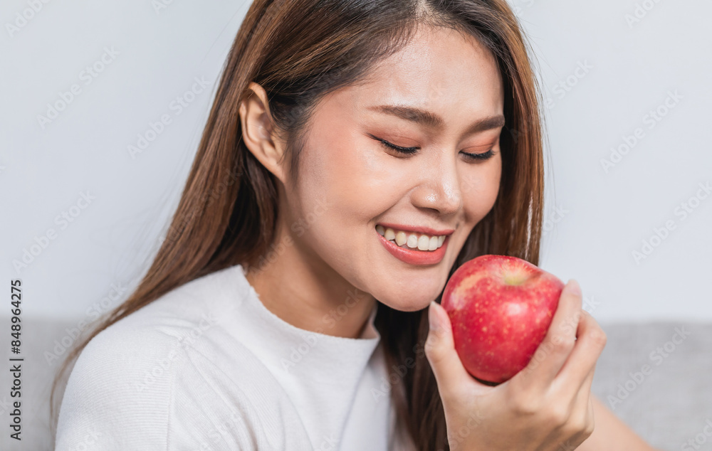 Young pretty woman eating red apple while sitting on the sofa at home Young pretty woman eating red apple while sitting on the sofa at home