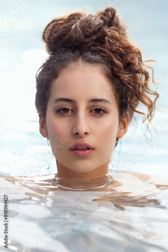 Skincare and Wellness close up portrait of a young woman with brown hair and beautiful skin in the water. Looking into the camera. 
