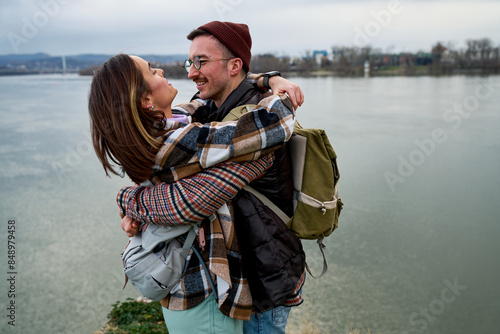 Joyful couple sharing a playful moment on a scenic riverbank, basking in their love.