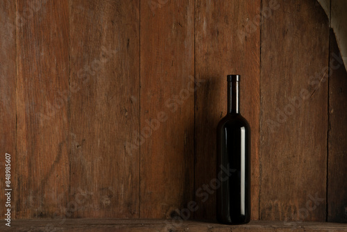 Bottle of red wine on a wooden background in a winery
