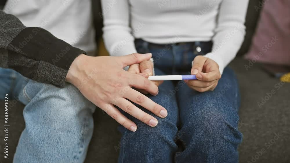 A man and woman holding a pregnancy test together in a living room, symbolizing anticipation and relationship. A man and woman holding a pregnancy test together in a living room, symbolizing anticipation and relationship.