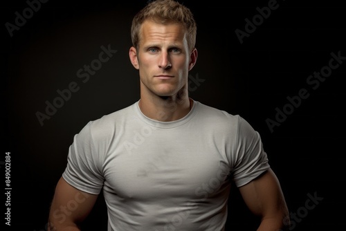 Portrait of a content man in his 30s wearing a moisture-wicking running shirt isolated in bare concrete or plaster wall