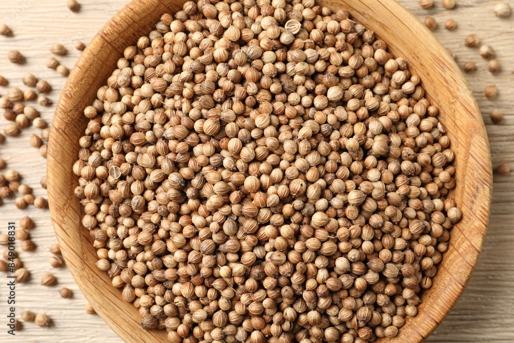 Dried coriander seeds in bowl on wooden table, top view Dried coriander seeds in bowl on wooden table, top view