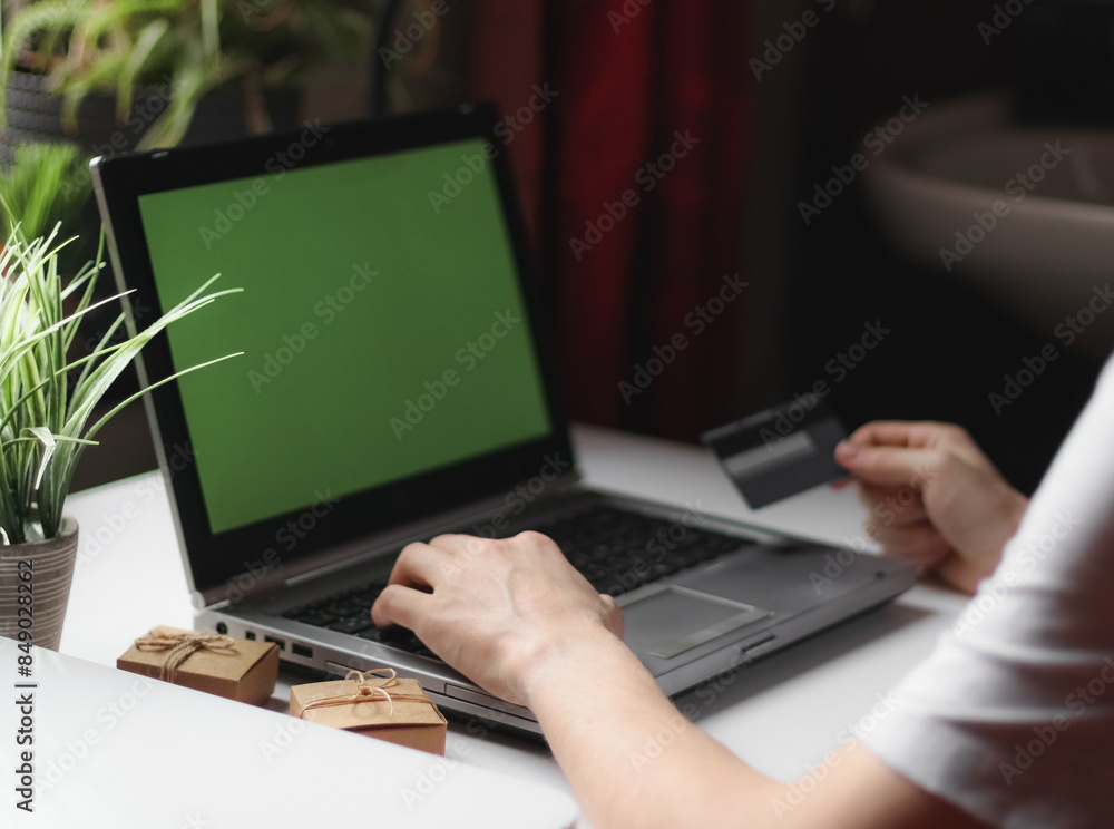 Young caucasian man in gray t-shirt doing online shopping sitting in a chair at a work desk Young caucasian man in gray t-shirt doing online shopping sitting in a chair at a work desk