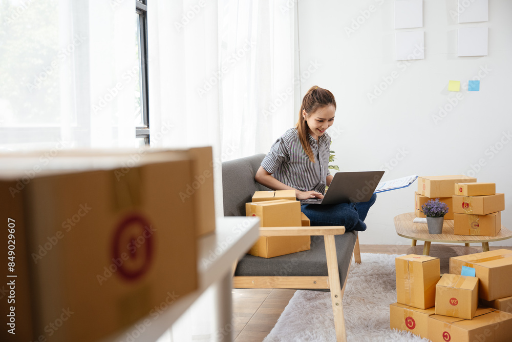 Owner SME Small and Medium Enterprises woman received orders from clients laptop then writing preparing products in parcel cardboard box packaging at home ready for delivery to customer Owner SME Small and Medium Enterprises woman received orders from clients laptop then writing preparing products in parcel cardboard box packaging at home ready for delivery to customer