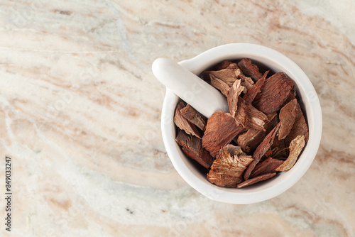 Top-view of Dry Organic Arjuna (Terminalia Arjuna) Barks, in white ceramic mortar and pestle, on a marble background. photo