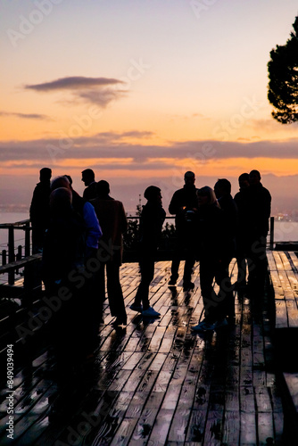 Silhouette of people socialising on wooden deck at sunrise