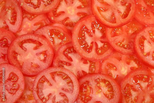 Red background, slices of ripe tomatoes in flat lay