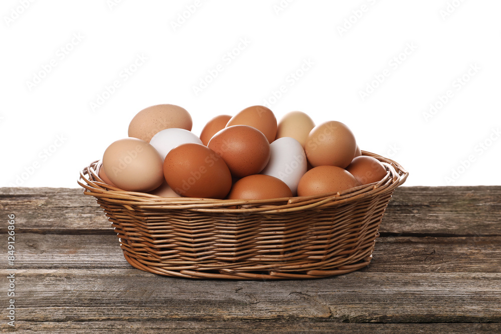 Fresh chicken eggs in wicker basket on wooden table against white background Fresh chicken eggs in wicker basket on wooden table against white background