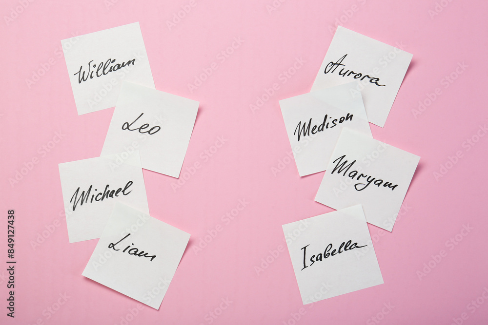 Paper stickers with different names on pink background, flat lay. Choosing baby's name Paper stickers with different names on pink background, flat lay. Choosing baby's name