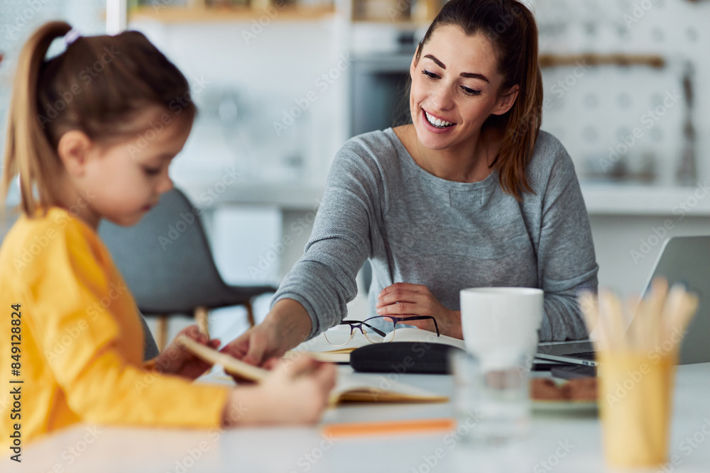 A loving mother helping her young daughter with homework A loving mother helping her young daughter with homework