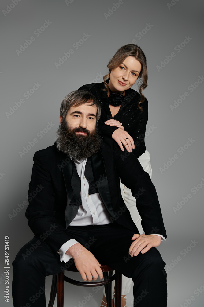 A loving couple in sophisticated attire pose together in a studio setting. A loving couple in sophisticated attire pose together in a studio setting.
