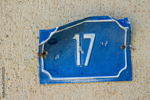 Old metal building number plaque on wall with number 17 photo