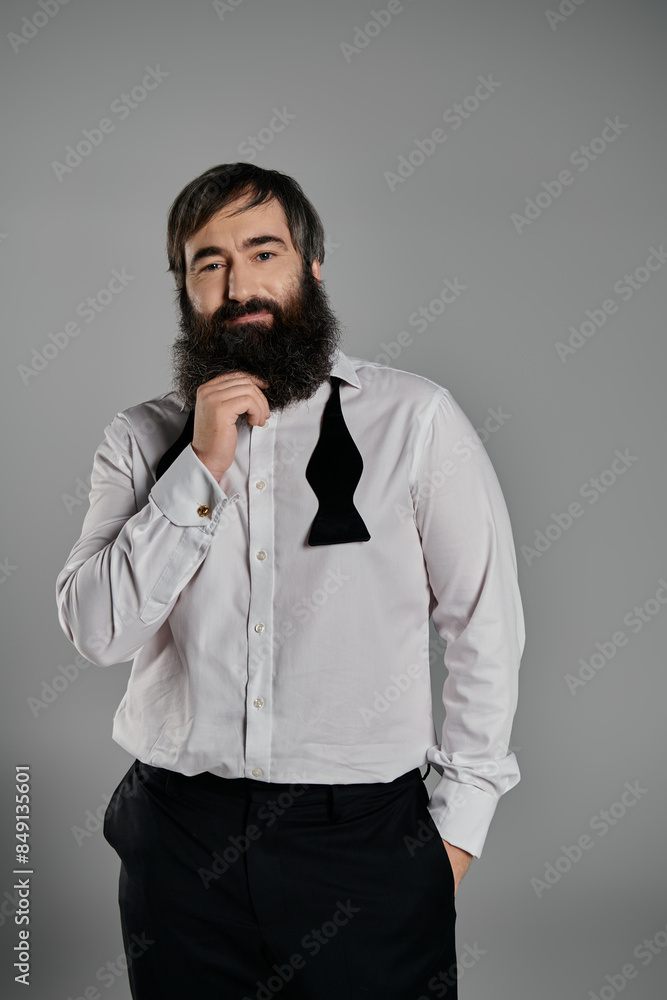 A man in a white shirt and black bow tie poses confidently against a gray background.