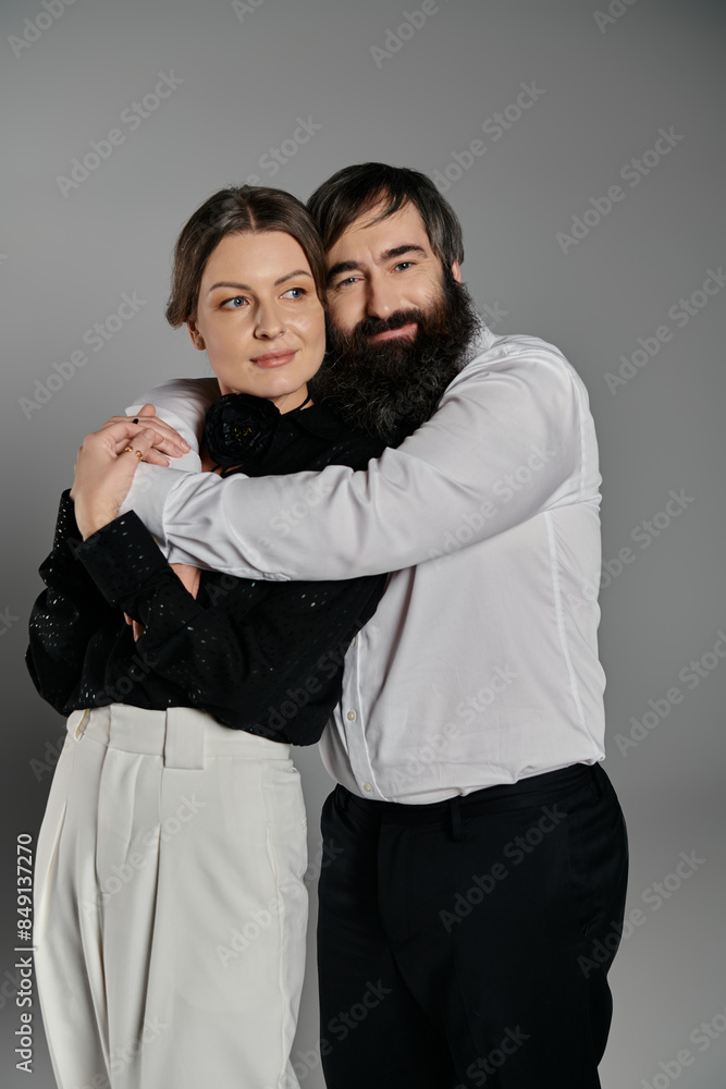 A loving couple dressed in elegant attire pose together for a portrait. A loving couple dressed in elegant attire pose together for a portrait.