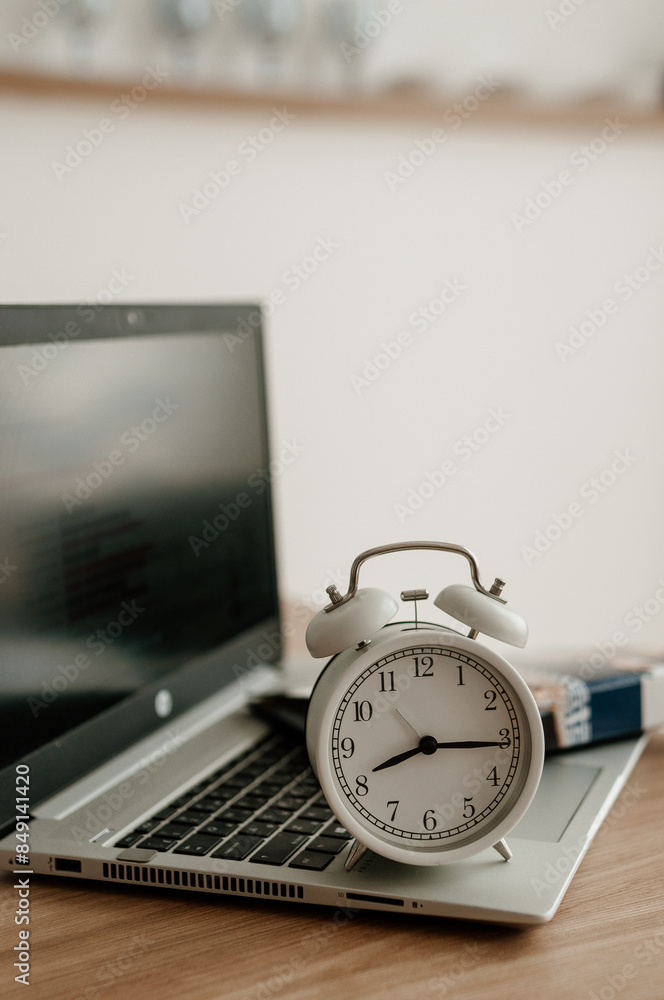 Fotografie alarm clock on desktop, laptop and notebook for work