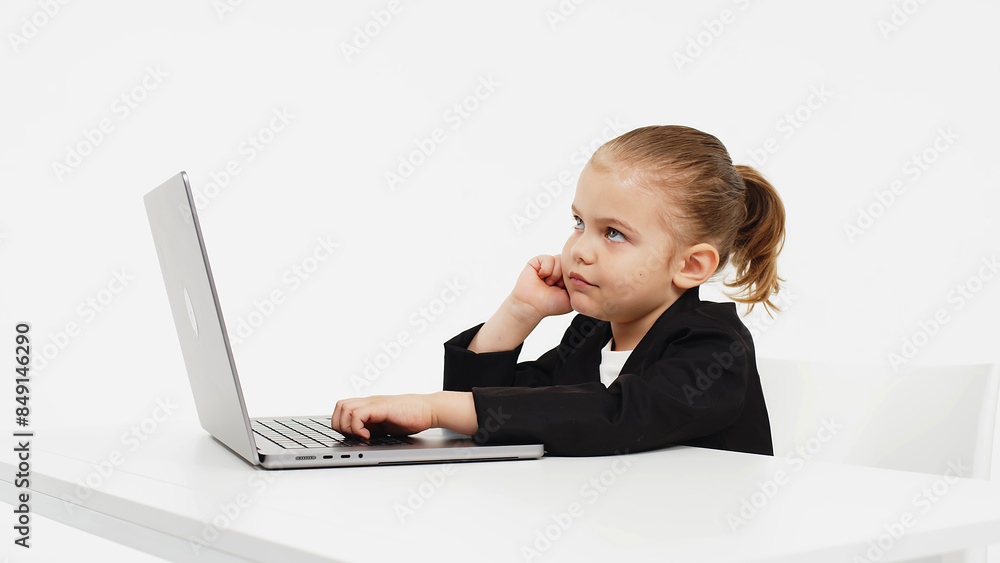 Business, little child working at a laptop on a light isolated studio background. Concept of deal, business and modern technology. Business, little child working at a laptop on a light isolated studio background. Concept of deal, business and modern technology.