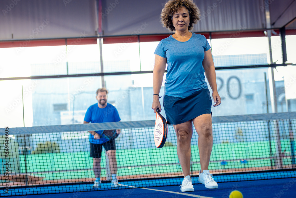 Mixed adult couple playing padel on outdoor court. Mixed adult couple playing padel on outdoor court.