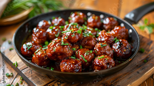 meatballs with chili sauce in the pan on wooden table, closeup view.