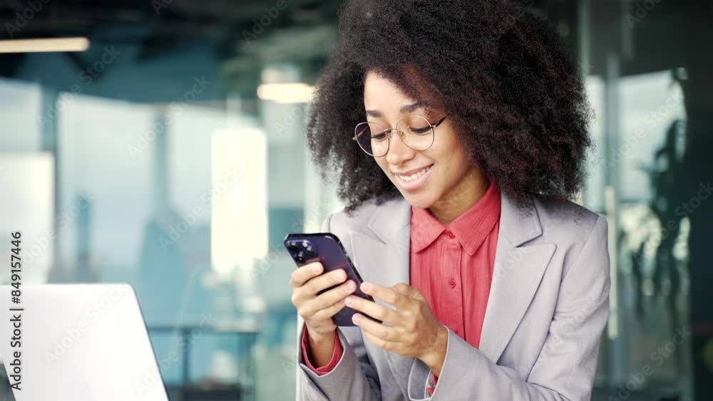 Happy excited young african american businesswoman read great news on phone sitting at workplace in business office. Black woman celebrates success, rejoices at win, smiles, shows gesture yes Close up Happy excited young african american businesswoman read great news on phone sitting at workplace in business office. Black woman celebrates success, rejoices at win, smiles, shows gesture yes Close up