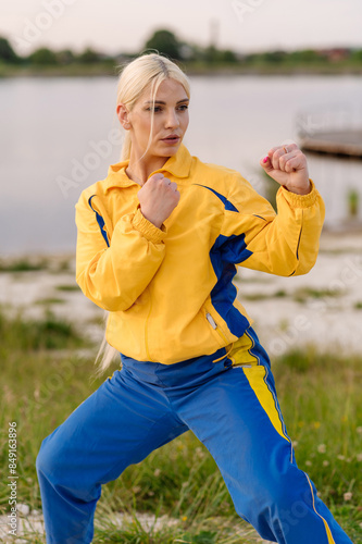 Strong woman karate fighter standing in fighting stance outdoors in park