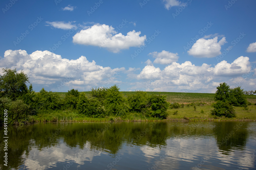 Tranquil scenery with a lake reflecting the blue sky and white clouds on a sunny day Tranquil scenery with a lake reflecting the blue sky and white clouds on a sunny day