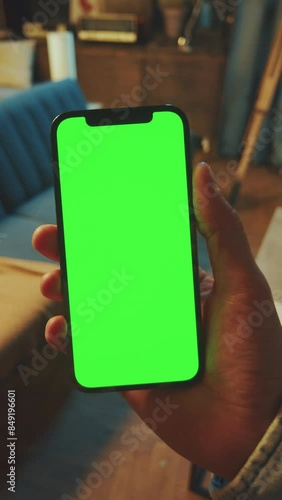 Close up hands man holds a scrolling phone with a vertical green screen in a dark room. Device. Smartphone. Social media