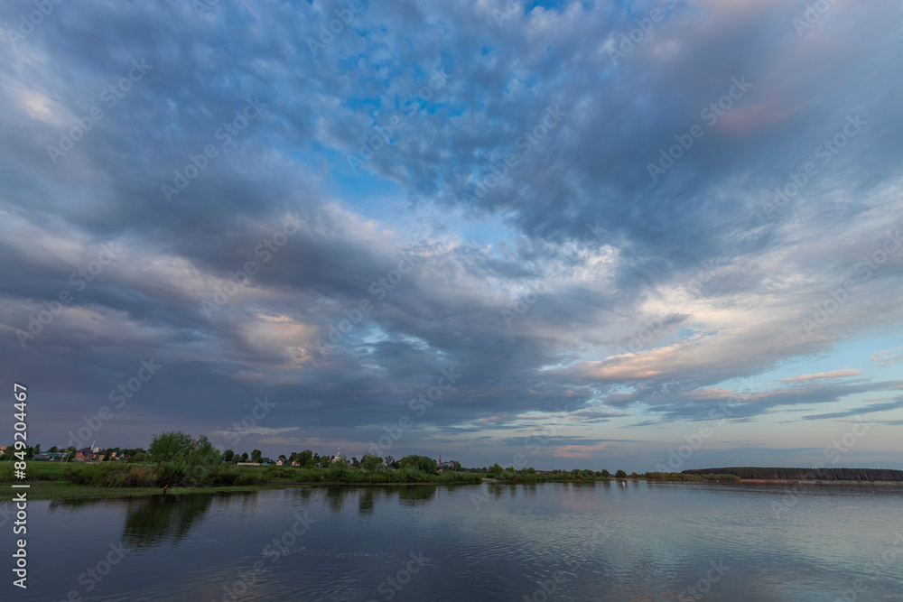 Calm waters reflect the pastel hues of the sky as fluffy clouds drift overhead, capturing the peaceful essence of a tranquil spring evening by the lake. Calm waters reflect the pastel hues of the sky as fluffy clouds drift overhead, capturing the peaceful essence of a tranquil spring evening by the lake.