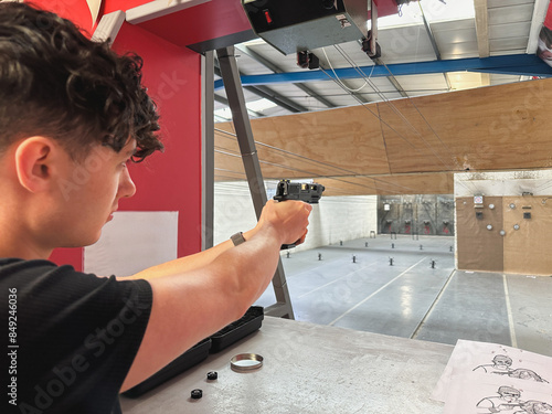 Young man aiming with an airgun at a target at a shooting range