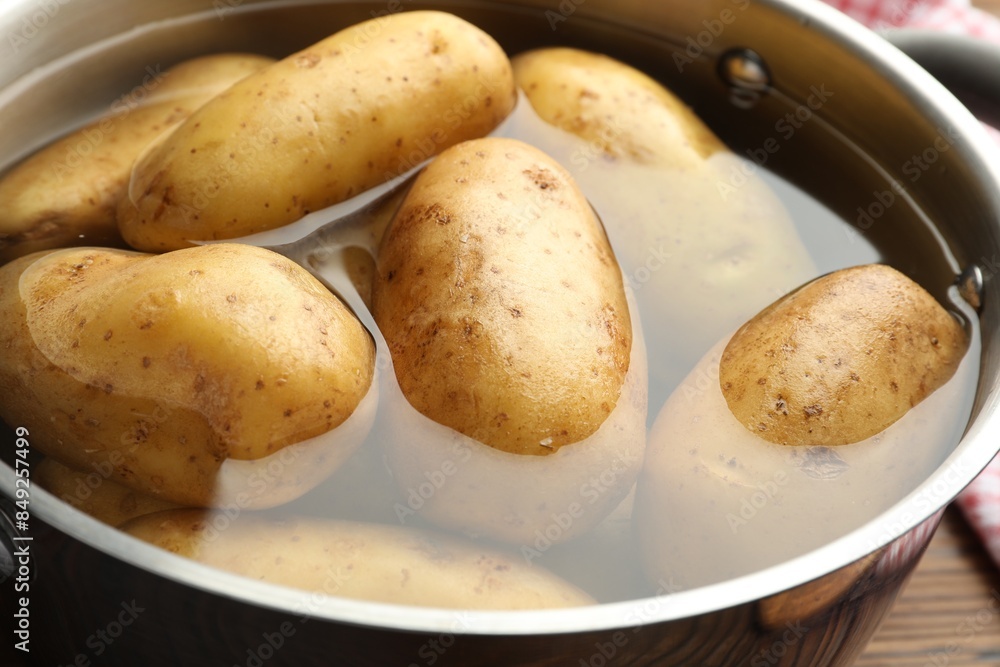 Raw potatoes in pot with water on table, closeup Raw potatoes in pot with water on table, closeup