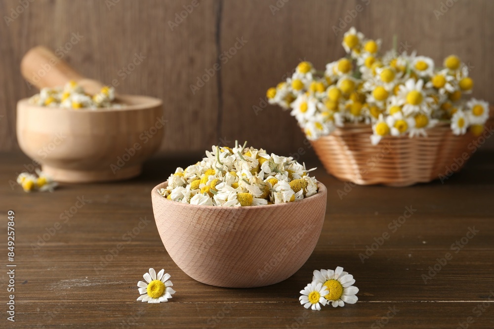 Dry and fresh chamomile flowers in bowl on wooden table Dry and fresh chamomile flowers in bowl on wooden table