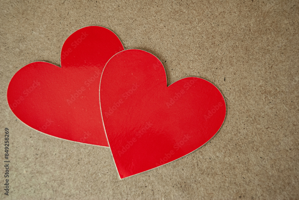 Two red hearts on a brown background, symbolizing love and warmth with a simple yet striking contrast. Two red hearts on a brown background, symbolizing love and warmth with a simple yet striking contrast.