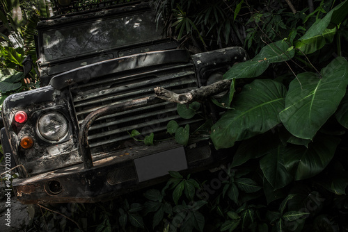 Fotografia Old broken dirty military jeep crashed into a tree in jungle tropical trees and